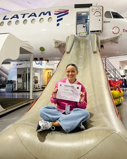 Isa com o certificado, no escorregador de treinamento da LATAM.
