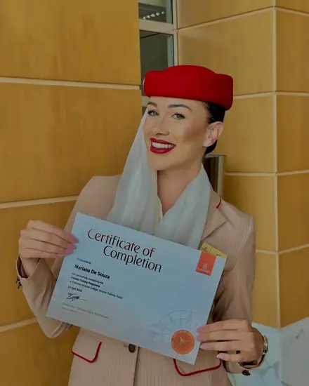 Mariana segurando o certificado de conclusão do treinamento da Emirates.